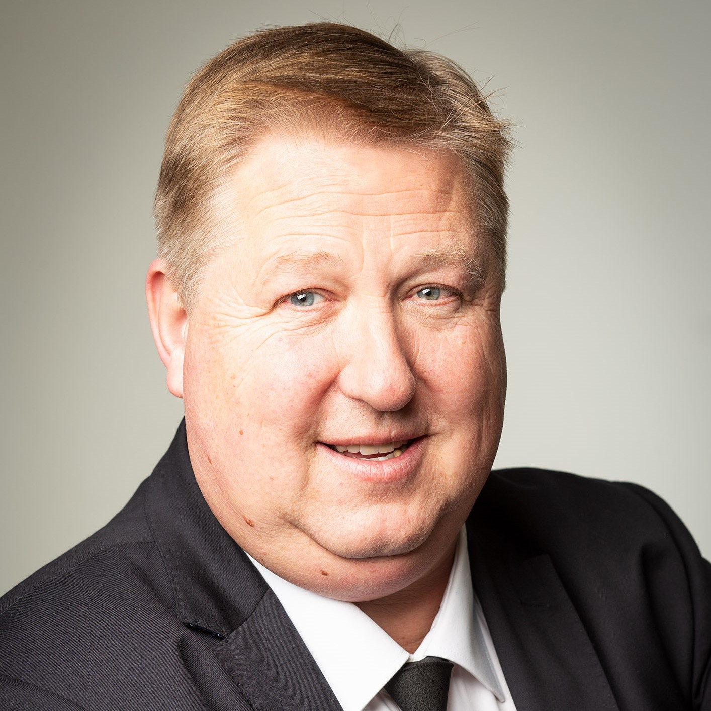 „Porträt eines freundlich blickenden Mannes im Anzug – professionelle Aufnahme für die Vorstellung des Teams oder der Unternehmensleitung.“